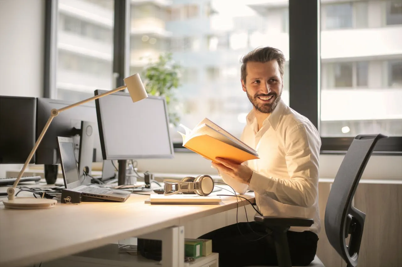 Tevreden klant aan zijn bureau met een boek in de hand